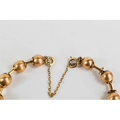 11 - A Victorian gold bracelet of ball and bar form, each ball textured with flower finial to either end,... 