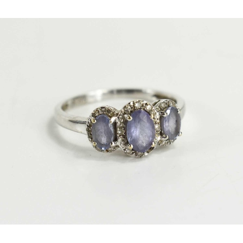 110 - A 9ct white gold and lavender amethyst and diamond three stone ring, the graduated oval amethysts ea... 