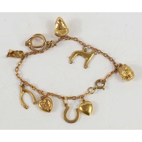 116 - A 9ct gold charm bracelet, with ten charms including wishbone, barrel, dog, heart, and others, 8.6g.