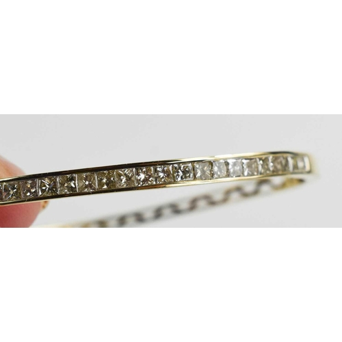 134 - A diamond and 9ct gold bangle, set with twenty two princess cut diamonds, each of approximately 0.05... 