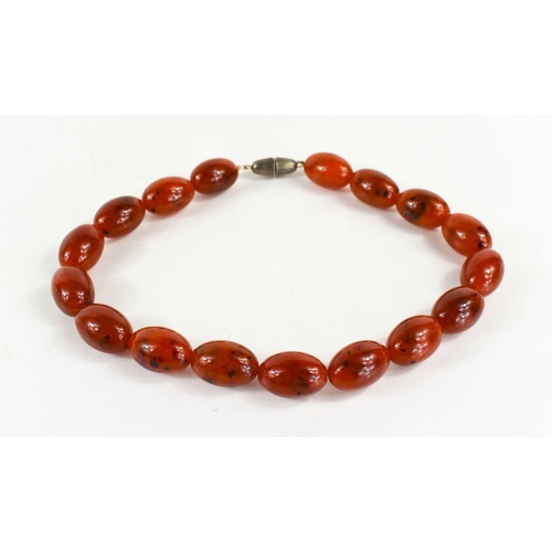 140 - A red amber beaded necklace, the oval beads measure approximately 2.5cm long, with a screw clasp, en... 