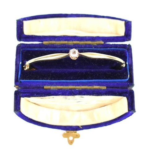 151 - An Edwardian gold bangle, inscribed, tests as 15ct with hinge and safety chain, 10.2g.
