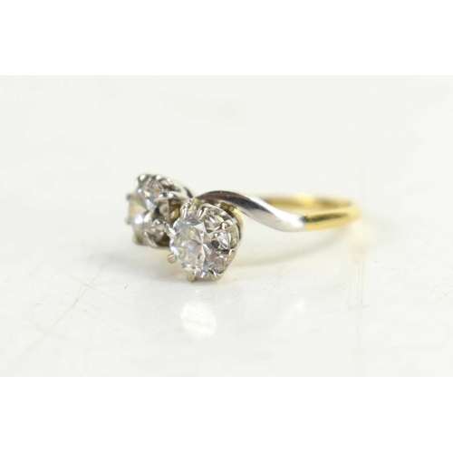 153 - An 18ct gold and diamond two stone cross over ring, the brilliant cut diamonds in eight claw setting... 
