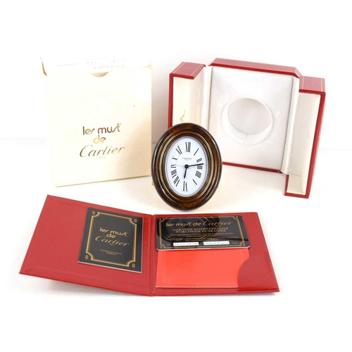 272 - A Must de Cartier Pendulette travel alarm clock, having a signed oval white enamel dial, with deep t... 