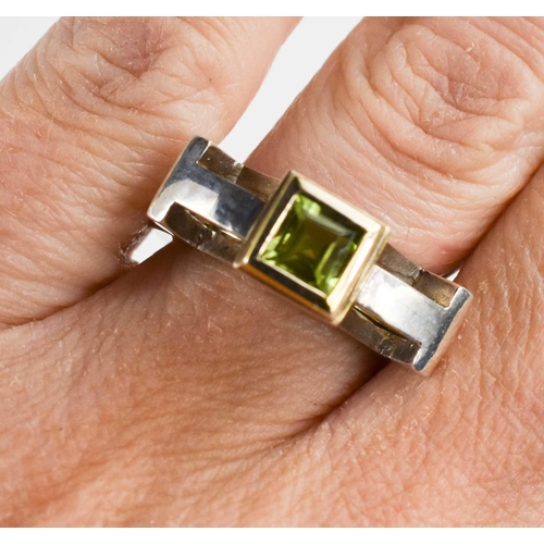 29 - A silver and parcel gilt ring, set with an emerald cut peridot, by jewellery designer Christopher An... 