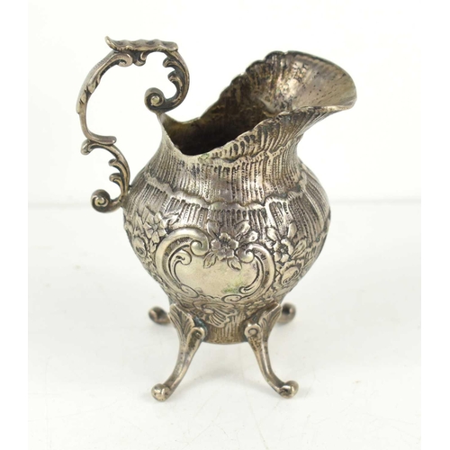 377 - A continental silver cream jug with repousse floral decoration centred by a vacant rococo scroll car... 