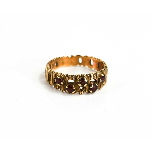 90 - A mid century modernist 9ct gold and garnet ring, the openwork bark textured band set with five garn... 
