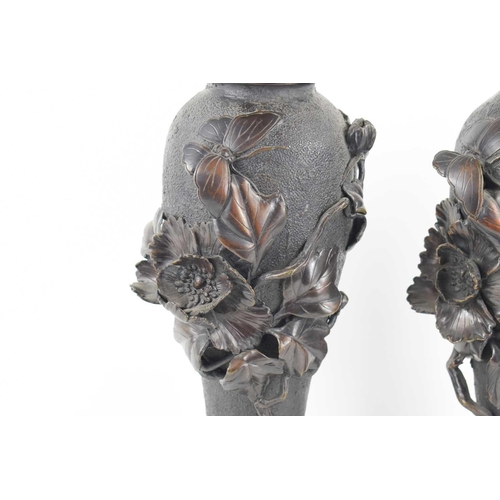 320 - A pair of Japanese bronze vases, with relief decoration depicting a butterfly among a sprays of flow... 