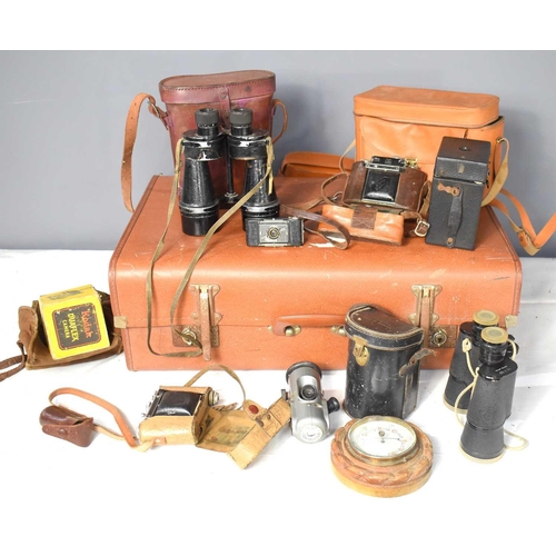 374 - A group of vintage cameras and binoculars inside a vintage suitcase to include an Ensign Midget.