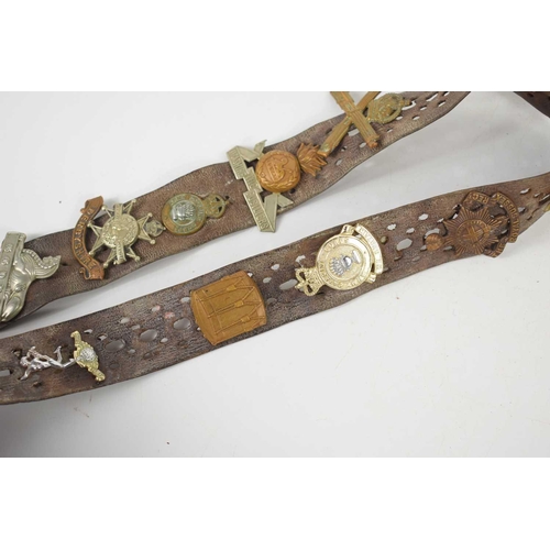 38 - A vintage leather belt adorned with various regimental cap badges, including the Royal Sussex, The D... 