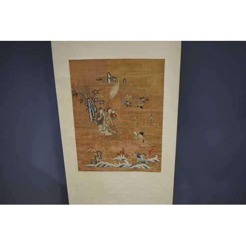 492 - A Chinese scroll with silk embroidered panel depicting two women holding a baby, with gentleman gest... 