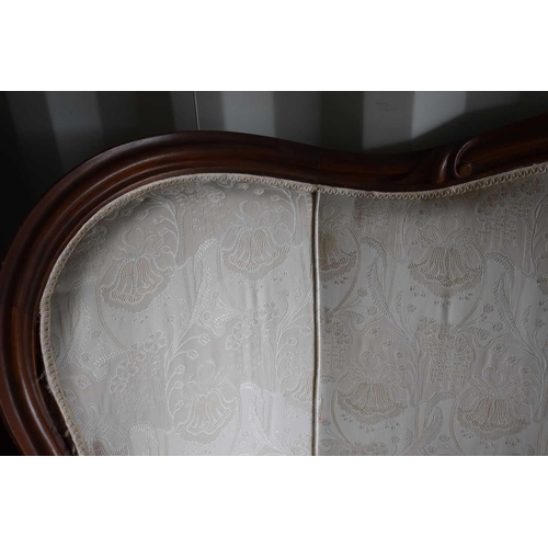 544 - A Victorian mahogany framed sofa, serpentine shaped back, upholstered in a cream floral fabric, rais... 