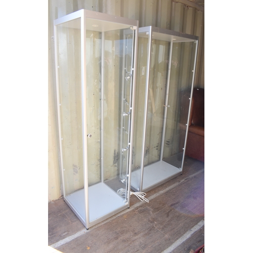 560 - Two modern glass display cabinets, with halogen light fittings and glass shelves.