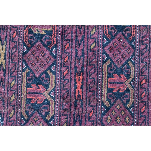 458 - A large deep red rug, possibly Bokhara, the central ground with repeating guls, and having a deep bo... 