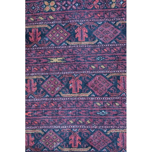 458 - A large deep red rug, possibly Bokhara, the central ground with repeating guls, and having a deep bo... 