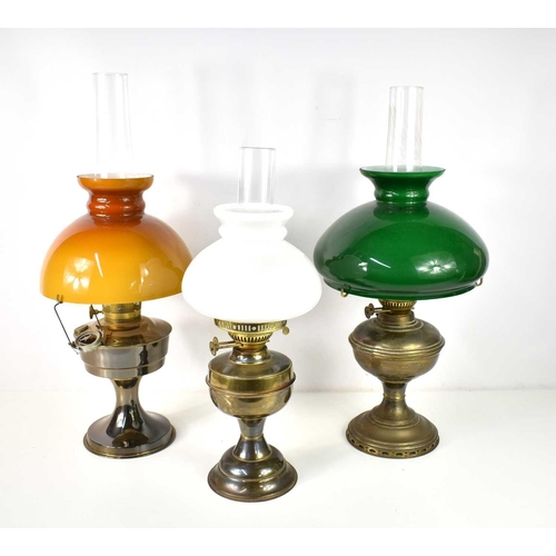 A group of three paraffin lamps, the largest with a green glass shade ...