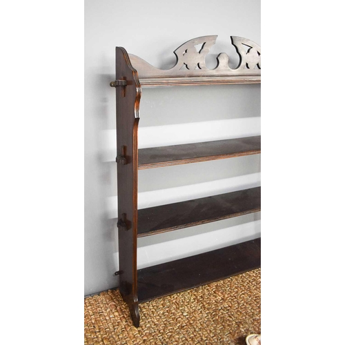 298 - A 19th century mahogany wall shelf, the shaped and pieced back rail adjoining two shaped side panels... 