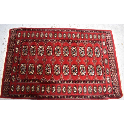 452 - A Middle Eastern red ground wool rug, with stylised ovals, and chevron borders, 130 by 85cm.