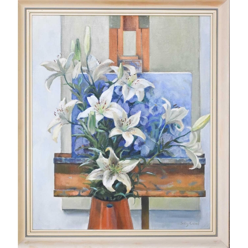63 - Sally Crew (British 20th Century): still life of Oriental lilies in a copper jug within an artist's ... 