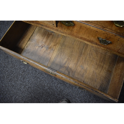 486 - An 18th century walnut chest of two over three drawers, with swan neck handles and brass lock plates... 