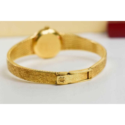 263 - An 18ct gold Omega ladies wristwatch, the circular dial with baton markers, and a 18ct gold bark eff... 