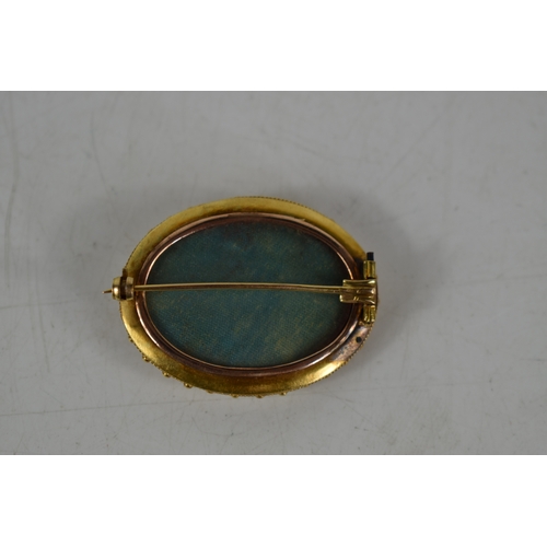 87 - A Victorian mourning brooch, of oval form with engraved decoration, glass back, total weight 8g.