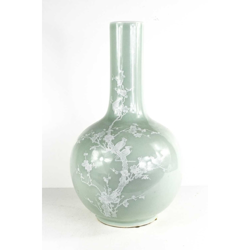 11 - A 20th century celadon pale green bottle vase, with white overglazed decoration depicting birds amid... 