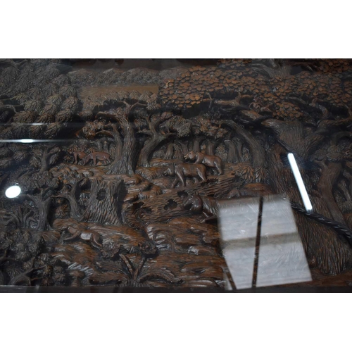 118 - A large carved Oriental hardwood dining table with glass top, the carvings depicting figures and arc... 