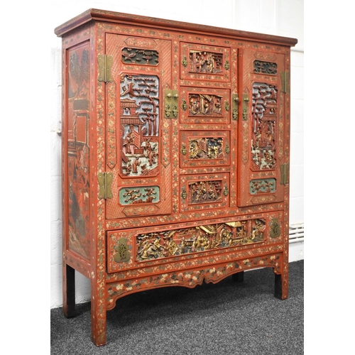 119 - An impressive 19th century Chinese red lacquered cabinet, profusely decorated with foliate scrollwor... 