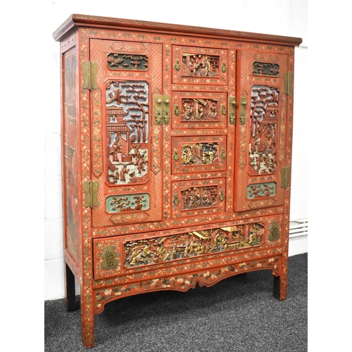 119 - An impressive 19th century Chinese red lacquered cabinet, profusely decorated with foliate scrollwor... 