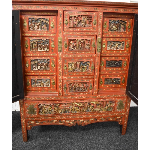 119 - An impressive 19th century Chinese red lacquered cabinet, profusely decorated with foliate scrollwor... 