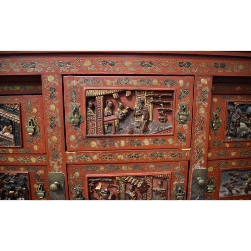 119 - An impressive 19th century Chinese red lacquered cabinet, profusely decorated with foliate scrollwor... 