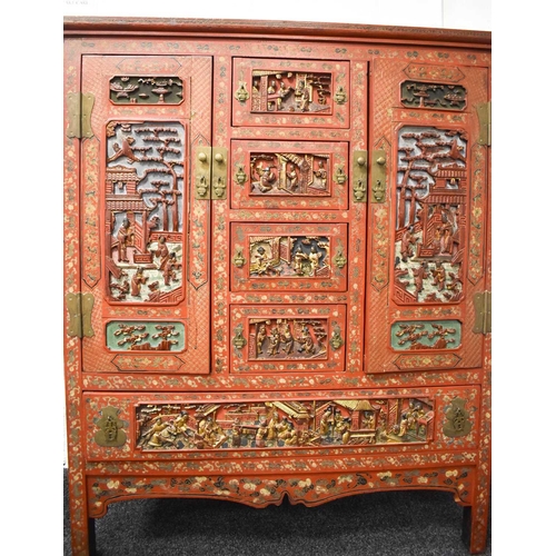 119 - An impressive 19th century Chinese red lacquered cabinet, profusely decorated with foliate scrollwor... 