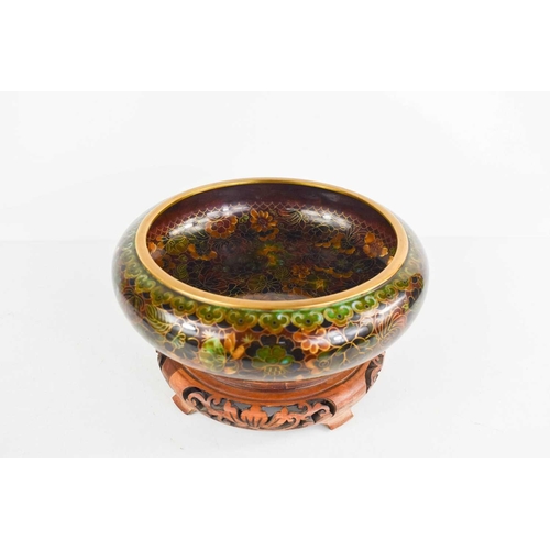 14 - A Chinese cloisonne enamel shallow bowl, circa 1920, depicting flowers and raised on a wooden carved... 