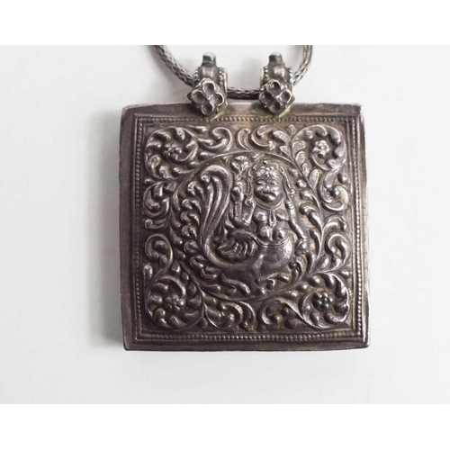 33 - An Indian white metal pendant necklace, the pendant embossed with a Kinnara; a mythical half bird-ha... 