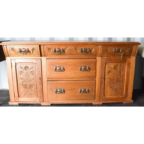 520 - An Art Nouveau style pine sideboard, with three upper frieze drawers carved with decoration, and two... 