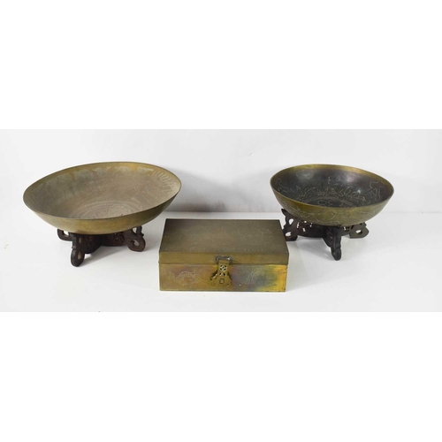 89 - Two Qing Dynasty brass bowls on wooden carved x-form stands, both decorated with foliate and calligr... 