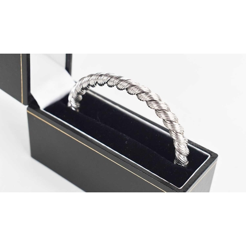 122 - A 9ct white gold bangle, of ropetwist form, hinged and with slide clasp and safety catch, 21g.