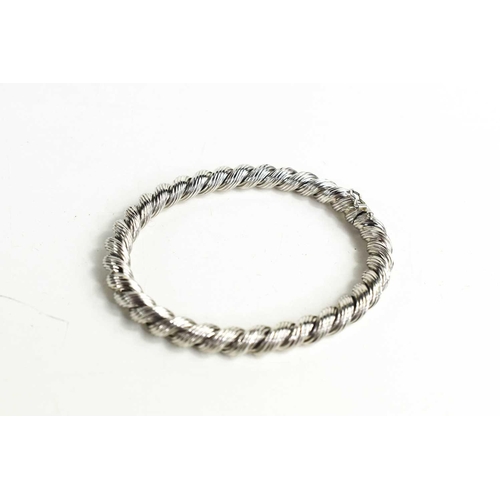 122 - A 9ct white gold bangle, of ropetwist form, hinged and with slide clasp and safety catch, 21g.