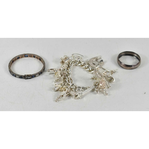 129 - A silver charm bracelet with twenty one charms together with a silver napkin ring and a white metal ... 