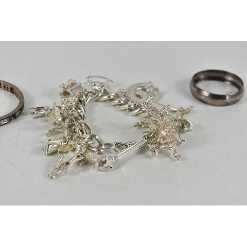 129 - A silver charm bracelet with twenty one charms together with a silver napkin ring and a white metal ... 