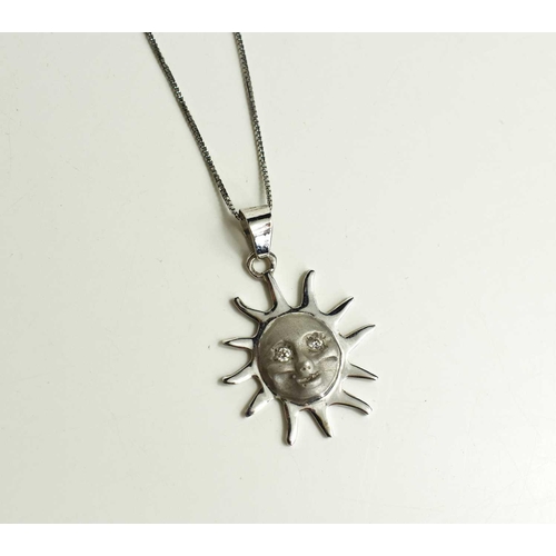 169 - An 18ct white gold necklace, the pendant in the form of a sun centred by a smiling face with brillia... 