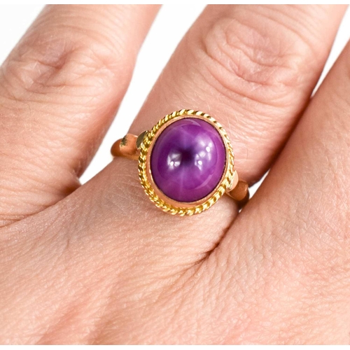 174 - An 18ct gold star ruby ring, the cabochon star ruby in an enclosed setting with ropetwist border, si... 