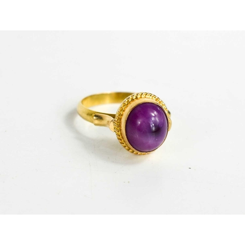 174 - An 18ct gold star ruby ring, the cabochon star ruby in an enclosed setting with ropetwist border, si... 