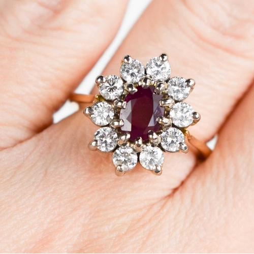 177 - An 18ct gold, ruby and diamond ring, the oval cut ruby bordered by ten brilliant cut diamonds, each ... 