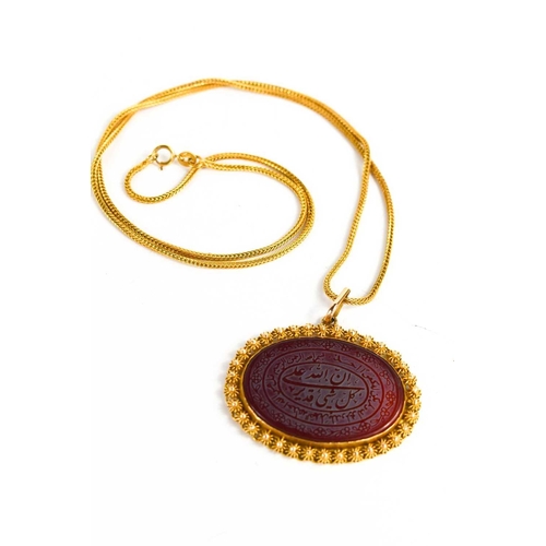 215 - A Persian gold and carnelian, the oval carnelian engraved with script within decorative borders, on ... 