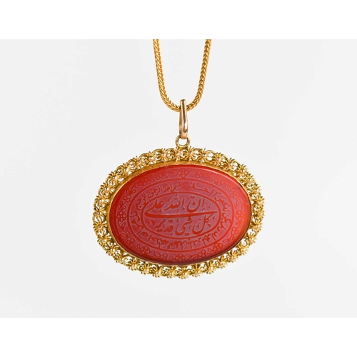 215 - A Persian gold and carnelian, the oval carnelian engraved with script within decorative borders, on ... 