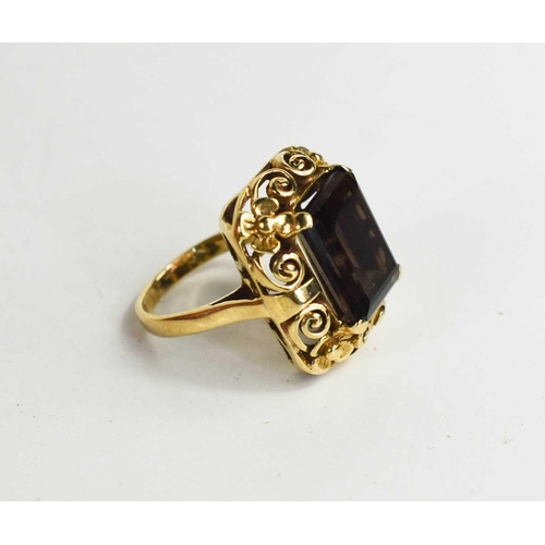 23 - A 9ct gold and smoky quartz ring, the rectangular cut quartz in a scroll and flower pierced setting,... 