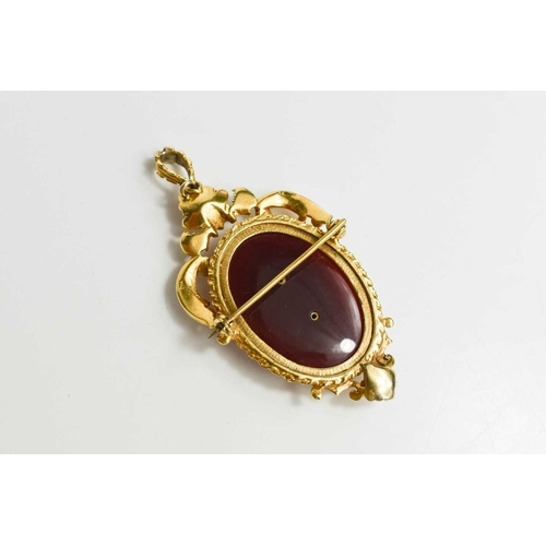 246 - A 9ct gold, diamond and carnelian pendant / brooch, the oval carnelian overlaid with a floral bouque... 