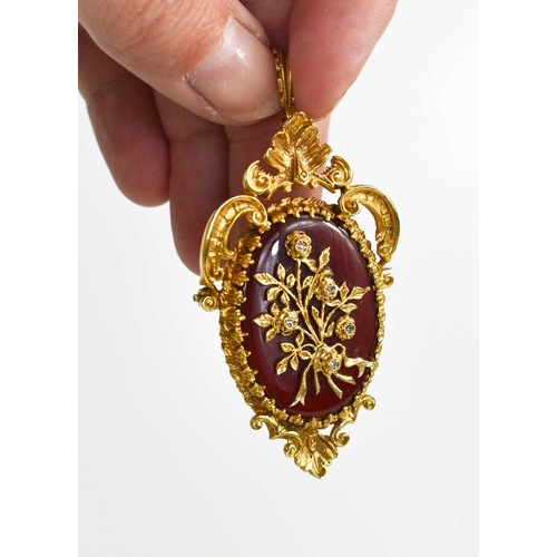 246 - A 9ct gold, diamond and carnelian pendant / brooch, the oval carnelian overlaid with a floral bouque... 